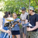Three students and a professor look at equipment while doing field research in Yellowstone National Park.