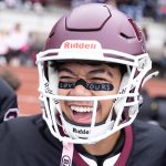 A football player smiles excitedly towards the camera.